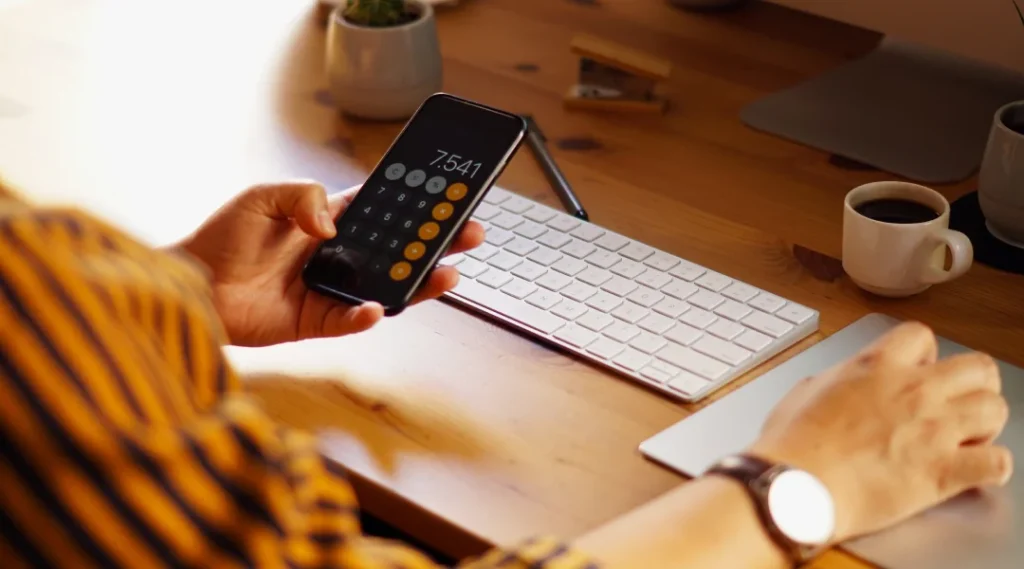 Une personne utilise un téléphone portable pour effectuer un paiement lié au calcul du prêt.