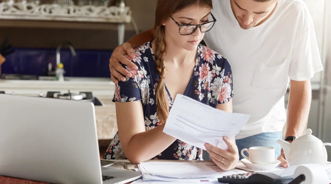 Un jeune couple examine ensemble leurs finances, discutant de l'emprunt pendant une proposition de consommateur.