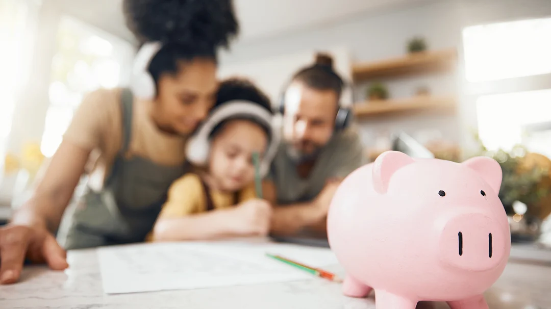 Une famille observe un cochon tirelire posé sur un bureau.
