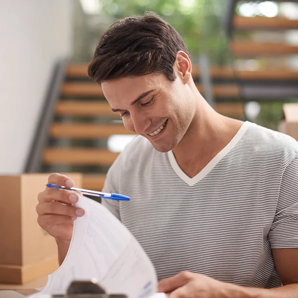 Un homme souriant tient un stylo et du papier.