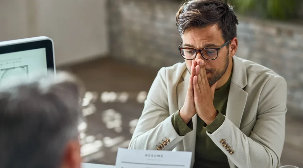 Un homme assis à un bureau, les mains sur le visage, semblant préoccupé par une situation d'insolvabilité.