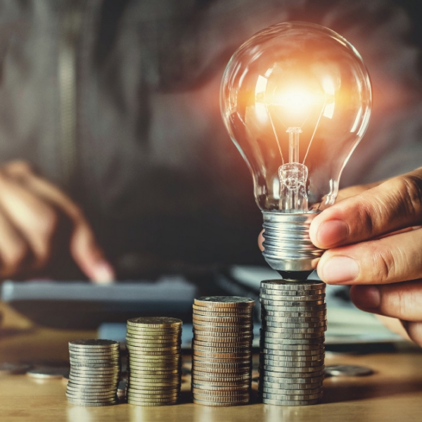 Ampoule posée sur des pièces de monnaie symbolisant les avantages du dépôt volontaire pour gérer ses dettes